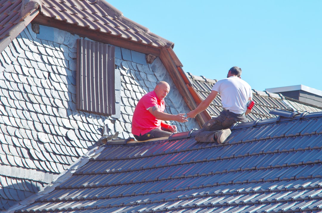 Deux couvreurs au travail sur la toiture d'une maison